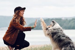 woman high-fiving her Australian Shepard