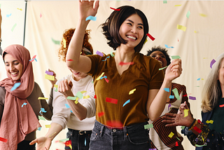 Action shote of mixed age multiethnic women celebrating by dancing with ticker tape. Credit: Southworks Creative Ltd