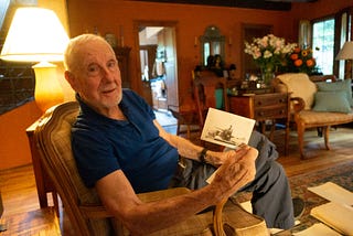 Joe Simboli holds a photo of himself in a WWII tank.