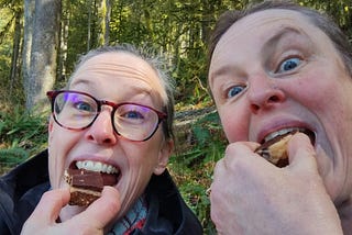 a photo of me and my sister eating Nanaimo Bars while taking a break from a hike at Buntzen Lake