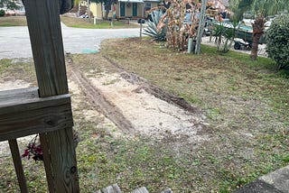 An empty driveway with deep muddy tire drag marks.