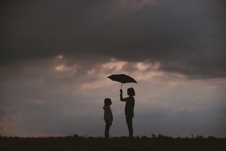 A girl holds an umbrella above her and a friend.