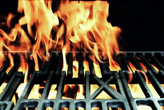 Stinging flames coming out of a grill. In the grill grate you can read the letters UX