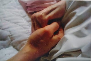 Photo of the author holding her mother’s hand in the latter’s bed