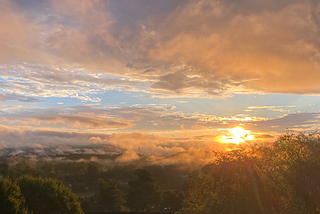 A fantastic sunrise with blue skies sandwiched between the ground and grey clouds.