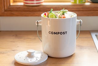 A cleanly-designed ceramic compost bin sitting on a kitchen counter