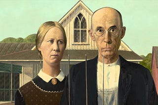 The artist Grant Wood’s 1930 painting “American Gothic.” A close up of a dour older farming man and woman standing together.