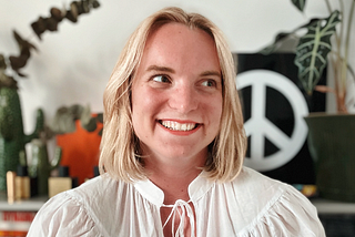 Nicole Michaelis, smiling in front of a peace sign
