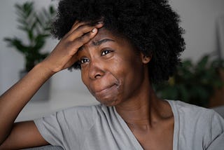 A picture of a young black woman who is sad and looks like she is on the verge of tears.