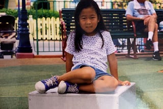 Small girl sitting on platform in park.