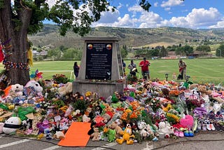 Memorial with flowers and indigenous community members honouring the lives of the 215 children lost at the Kamloops Residential School