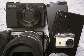 ensemble of digital cameras and cellphone cameras on light background