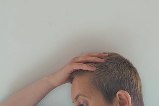 Woman with short hair holds her head in her hand