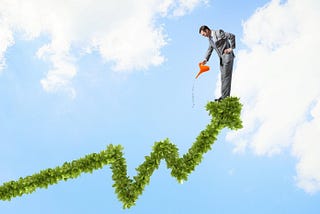 Young cheerful businessman watering green growing graph line/equity curve with watering can in sky