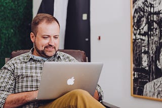 A man using an apple laptop in a white office