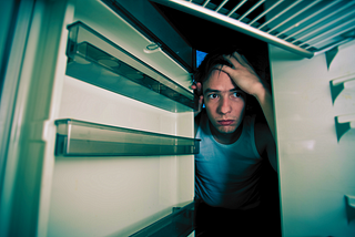 A man peering into his empty refrigerator.