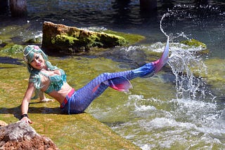 White woman dressed as a mermaid splashing in the water