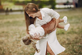 Mother with little daughter playing in a summer park