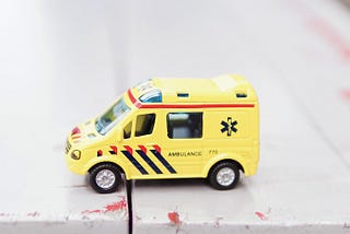 Yellow ambulance toy on white surface