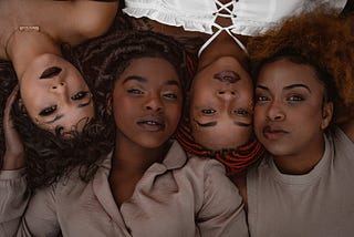 Four Black womxn with natural hair in nuetral colors