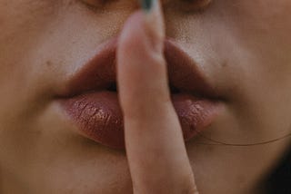 A woman’s mouth covered by her index finger