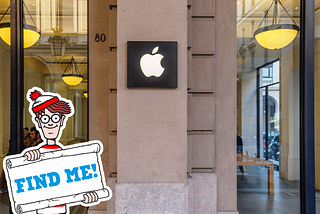 Image depicting an Apple store facade with the iconic ‘Where’s Waldo?’ character prominently holding a sign that reads ‘Find me!’ in the foreground.