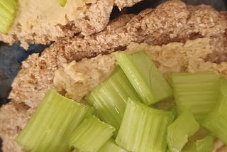 Coconut Rice bread with hummus and celery topping.