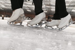 Close-up of three sets of figure skates on ice