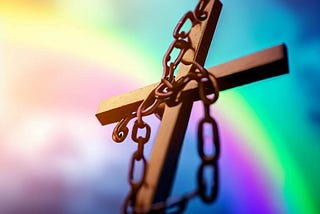 A cross is chained and taken down before a rainbow.