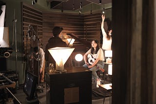 Film crew with young musician in dim music studio