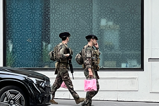 Two soldiers carrying machine guns and pink shopping bags.