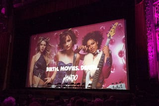 An image of Josie and the Pussycats doused in pink and purple in the Ace Hotel theater.