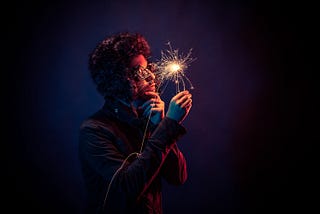 A man with a furry hat holding a sparkler.
