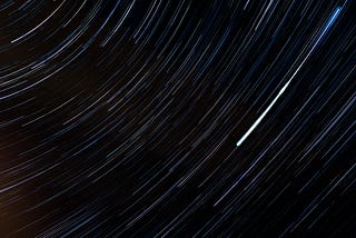 A long exposure photo of the sky, showing the stars moving in circular arcs as the night progresses