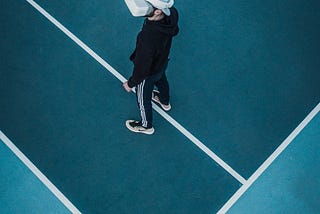 Man in tracksuit wearing virtual reality headset standing on a tennis court