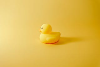 A yellow plastic duck on a yellow background.