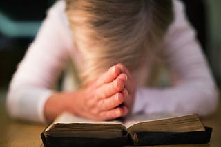 A woman prays over a bible.