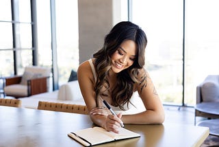 woman smiling down about to write in her journal