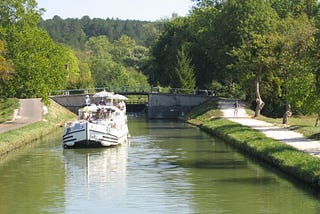 A renovated barge floats on the serene water of the Nivernais Canal in Burgundy, France.