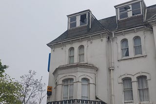 Old hotel with broken window and pigeon sitting on the glass.