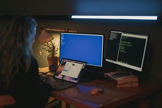 Woman sat at a computer, looking at code.