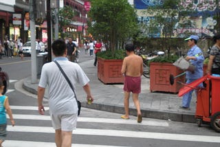 A man casually walks in the middle of a busy Shanghai street wearing nothing else than a pair of boxers and sandals.