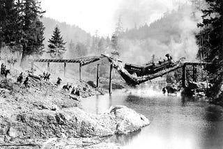 #praCegoVer fotografia preto e branca de um rio com sua ponte quebrando com um trem no meio