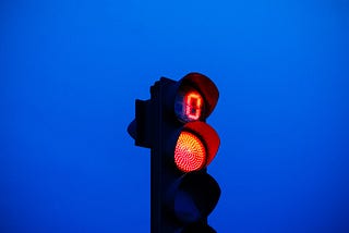 Red traffic light against blue sky.