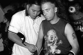 A Taiwanese referee straps boxing gloves onto the fists of the story’s author, who stares ahead with grim determination.