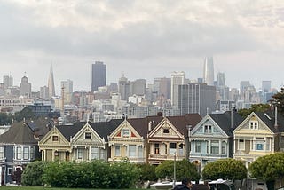 San Francisco’s iconic Victorians are surrounded, as always, by the backdrop of the City under foggy skies full of foreboding.