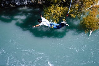 A man during a bungee jump over the river.