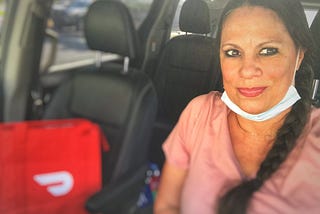 a photo of a DoorDash app dasher driver with their red dasher bag, in a van