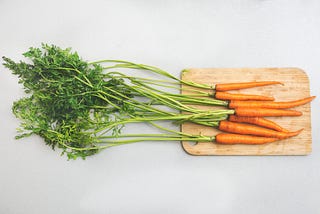 7 garden carrots on a chopping board.