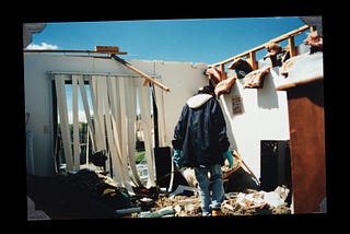 Person walking through debris of apartment with no roof overhead